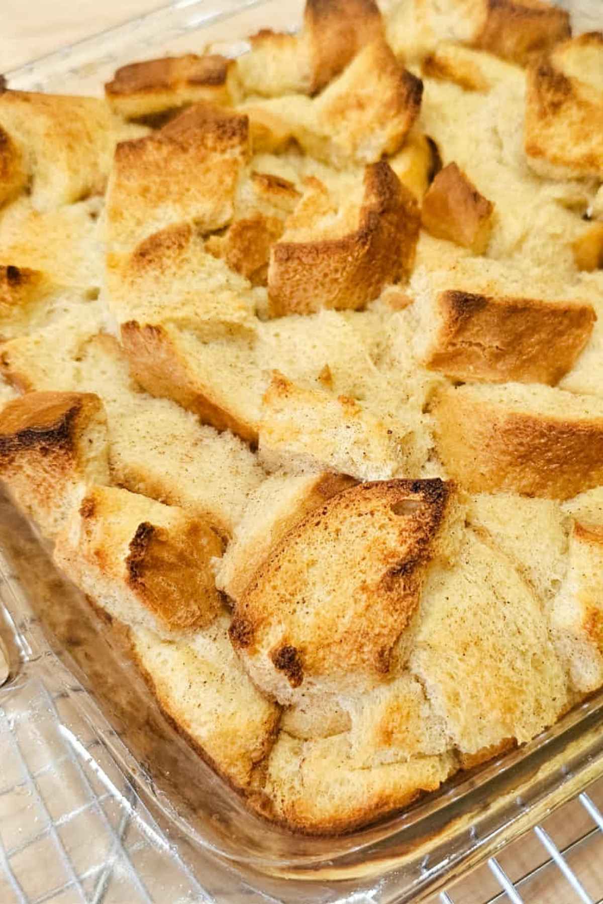 a close up picture of the cinnamon bread pudding sitting on a wire rack cooling
