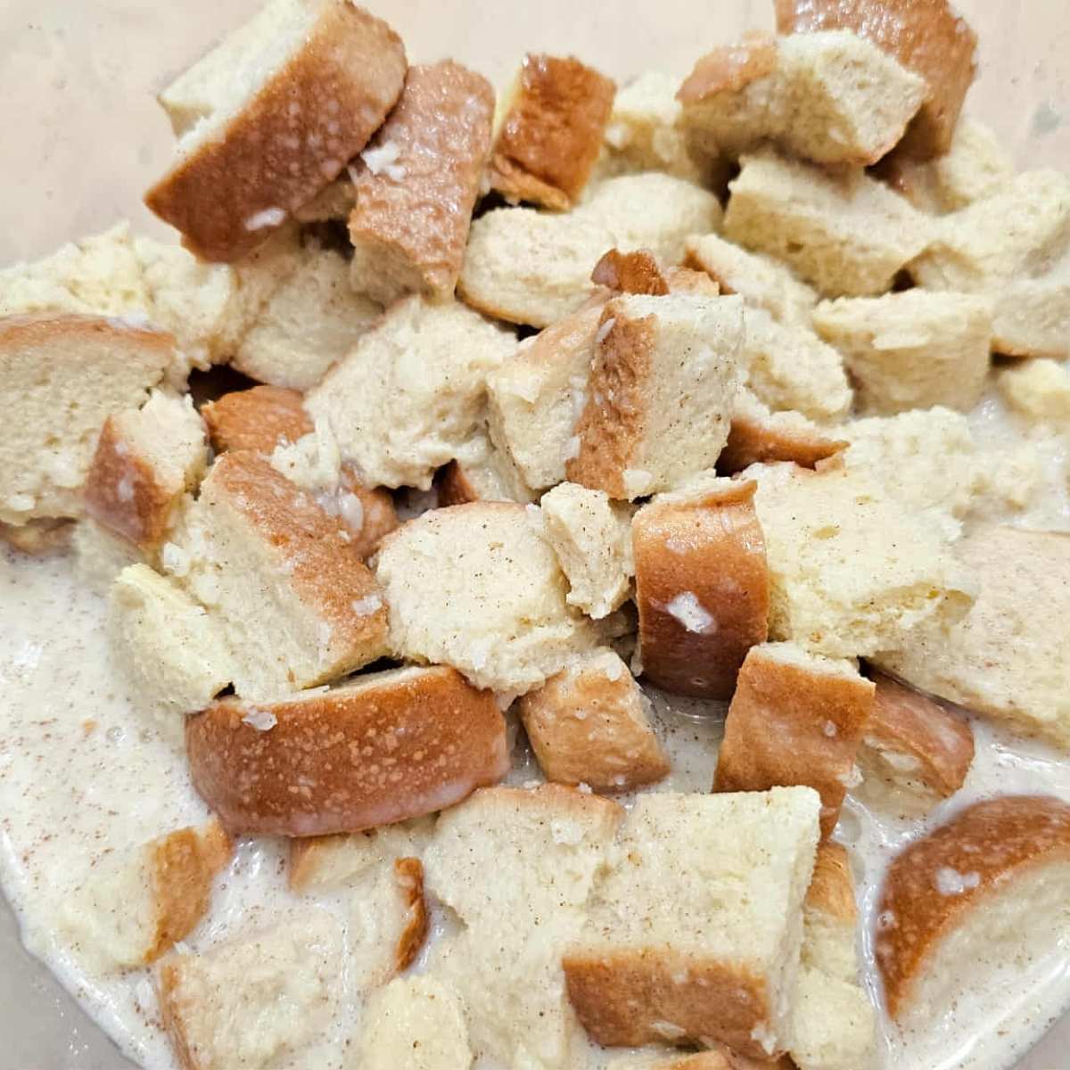 bread cubes added to the wet ingredients in a medium bowl.