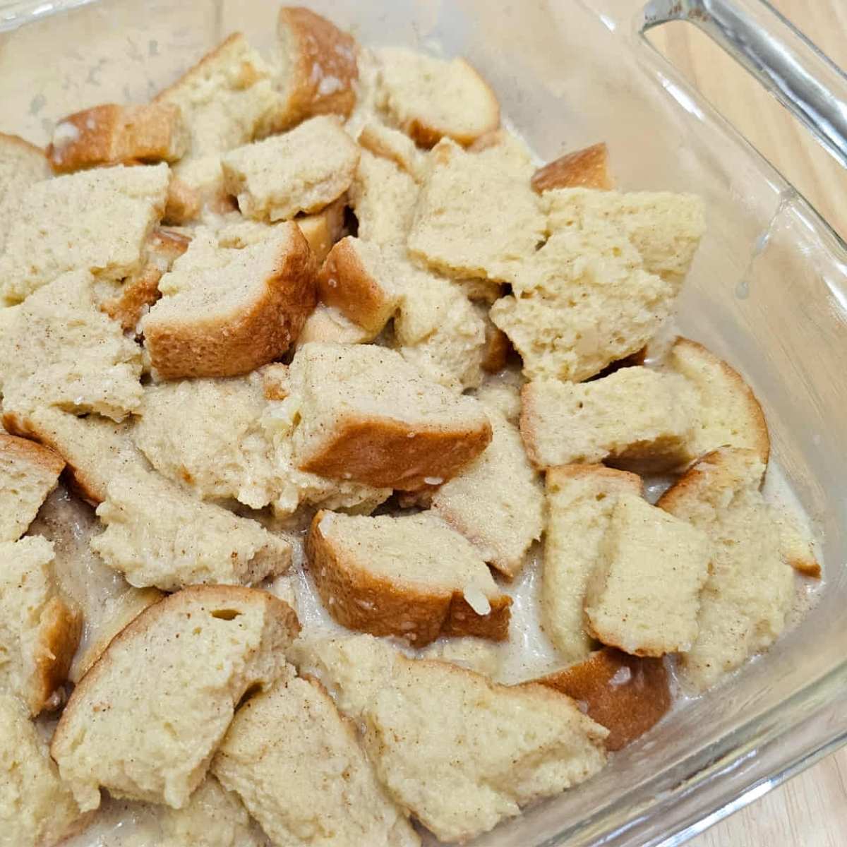 bread pudding mixture sitting in an 8x8 glass casserole and about to go in the oven