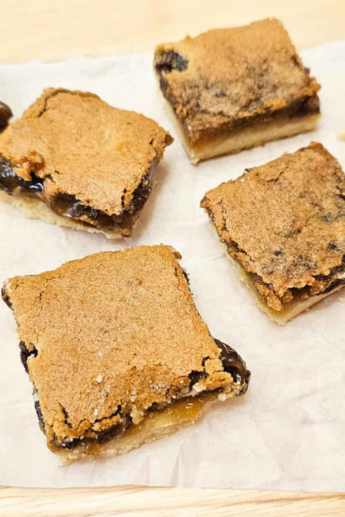 4 butter tart squares, close up on the tops of them sitting on a piece of parchment paper