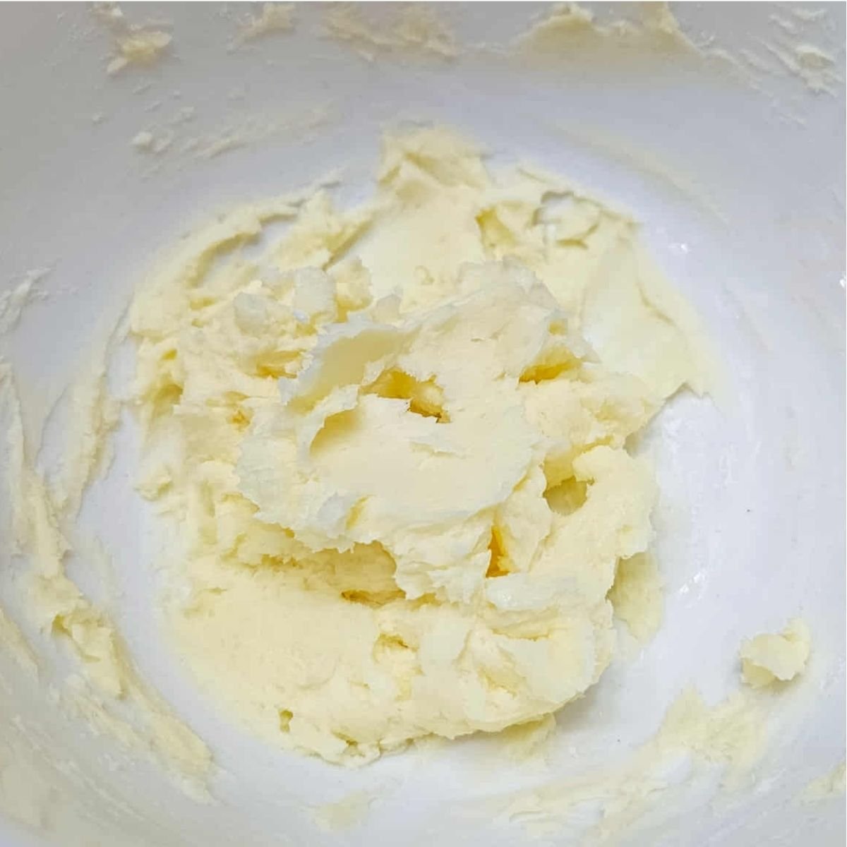 butter and icing sugar mixed together in a white glass bowl
