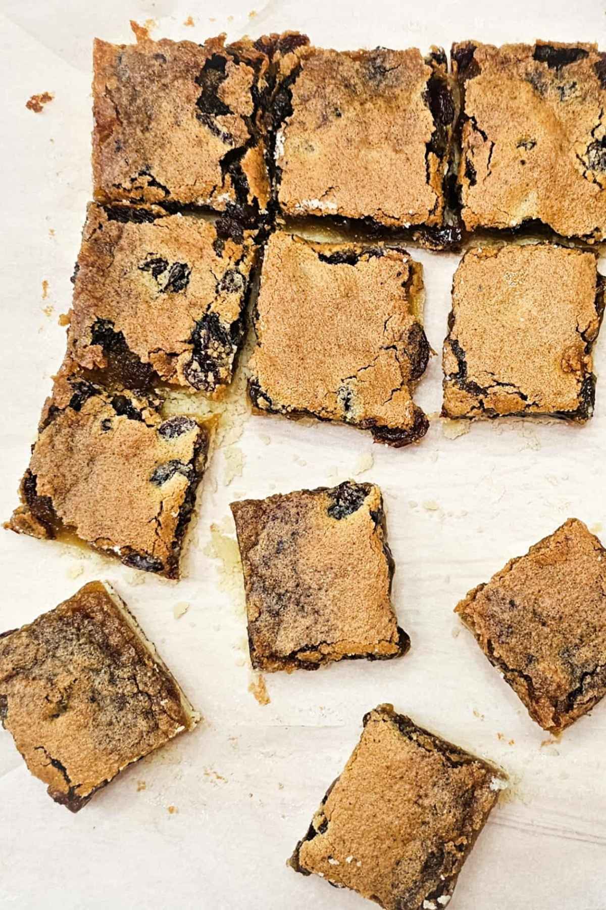 Butter tart squares that are sliced and spread out across a piece of parchment paper