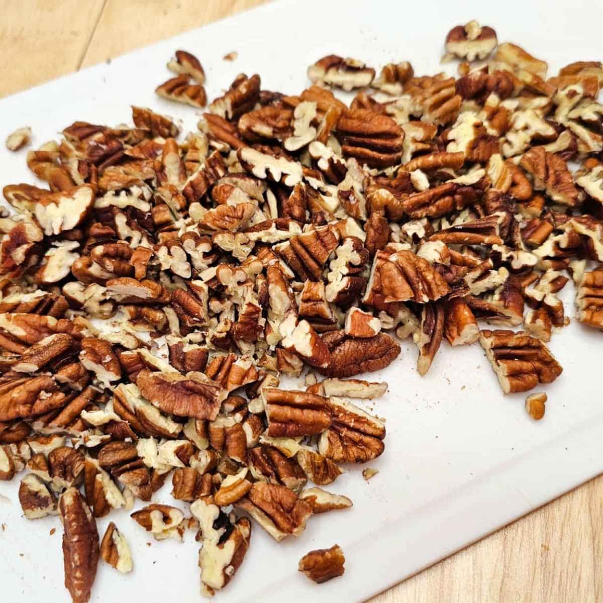 roughly chopped pecans sitting on a white cutting board