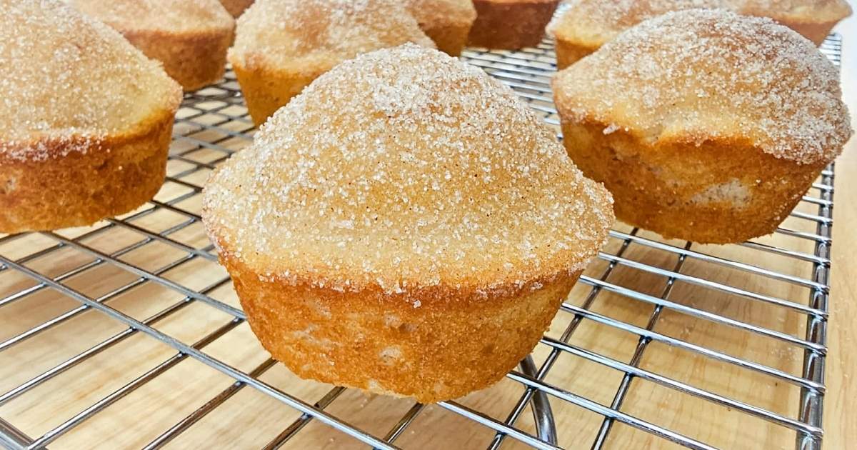 cinnamon sugar muffins sitting on a wire rack cooling on a wooden table