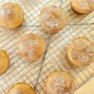 cinnamon sugar muffins on a wire rack cooling on a wooden table