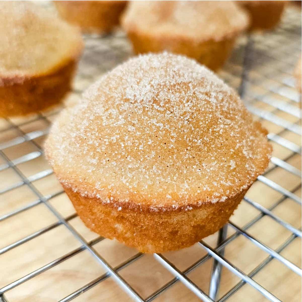 cinnamon sugar muffins sitting on a wire rack that was just dipped in butter and cinnamon sugar