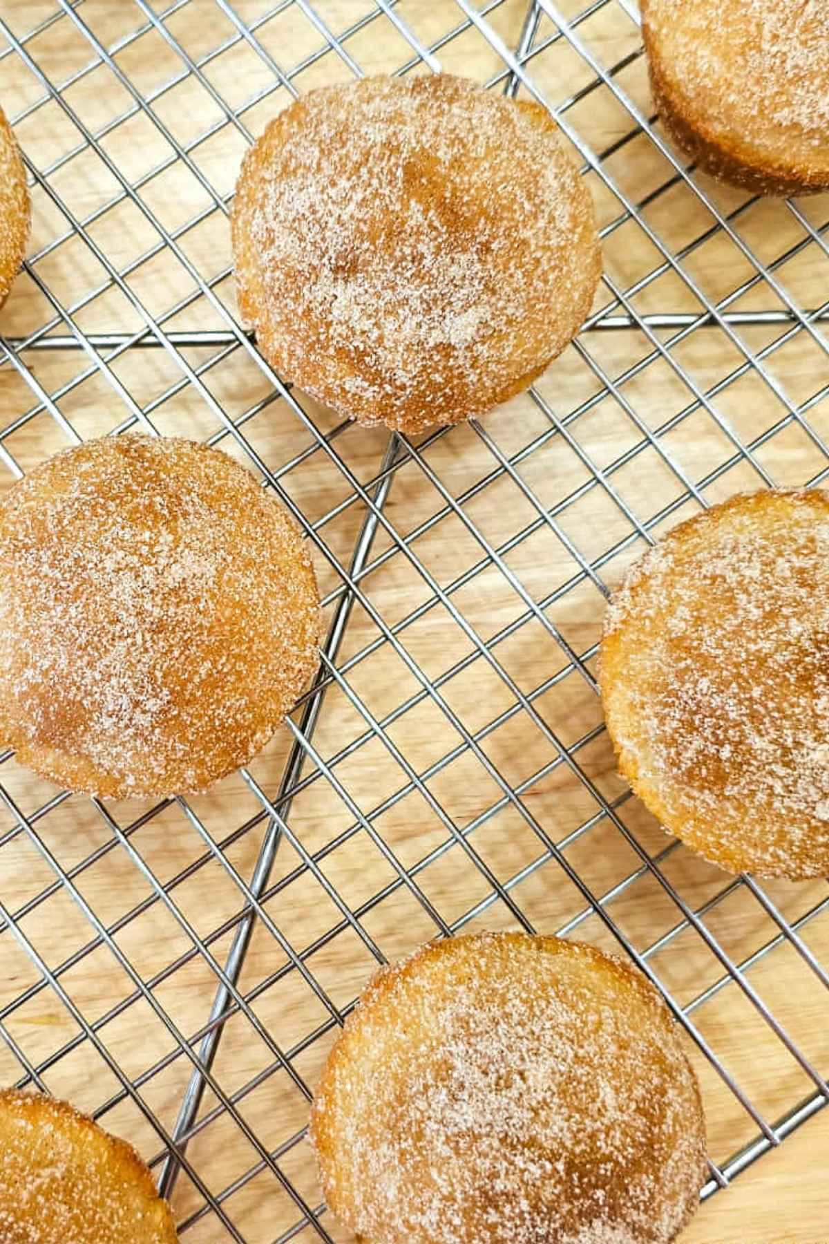 cinnamon sugar muffins sitting on a wire rack cooling on a wooden table