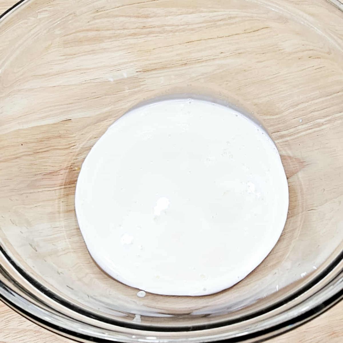 heavy cream and pure maple syrup in a clear glass bowl on a wooden counter top