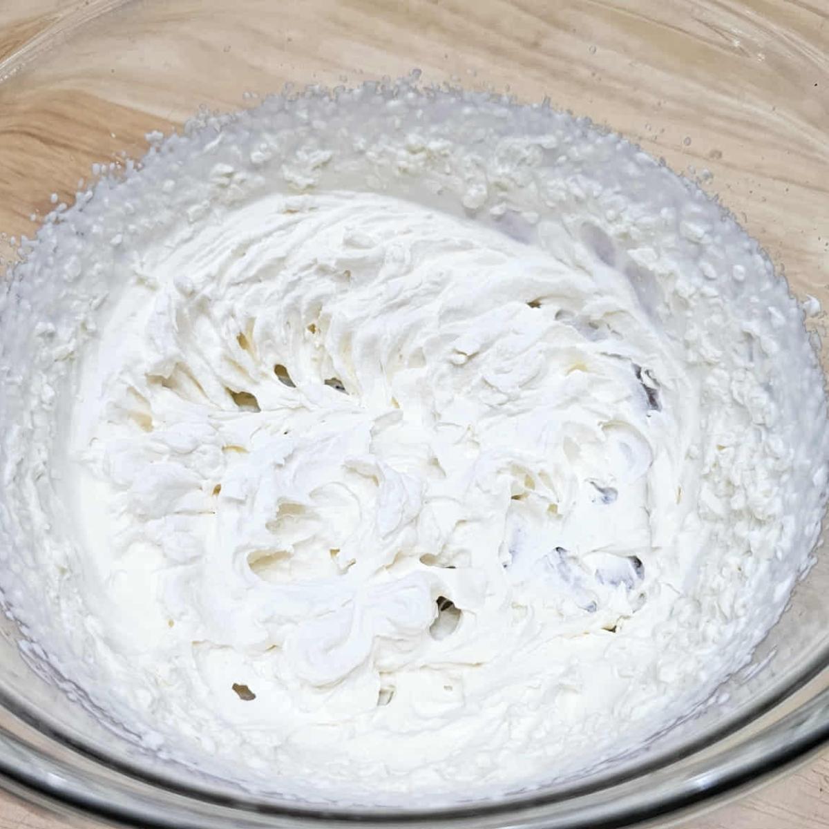 heavy cream and pure maple syrup whipped by the electric beaters and sitting in a glass clear bowl on a wooden counter top