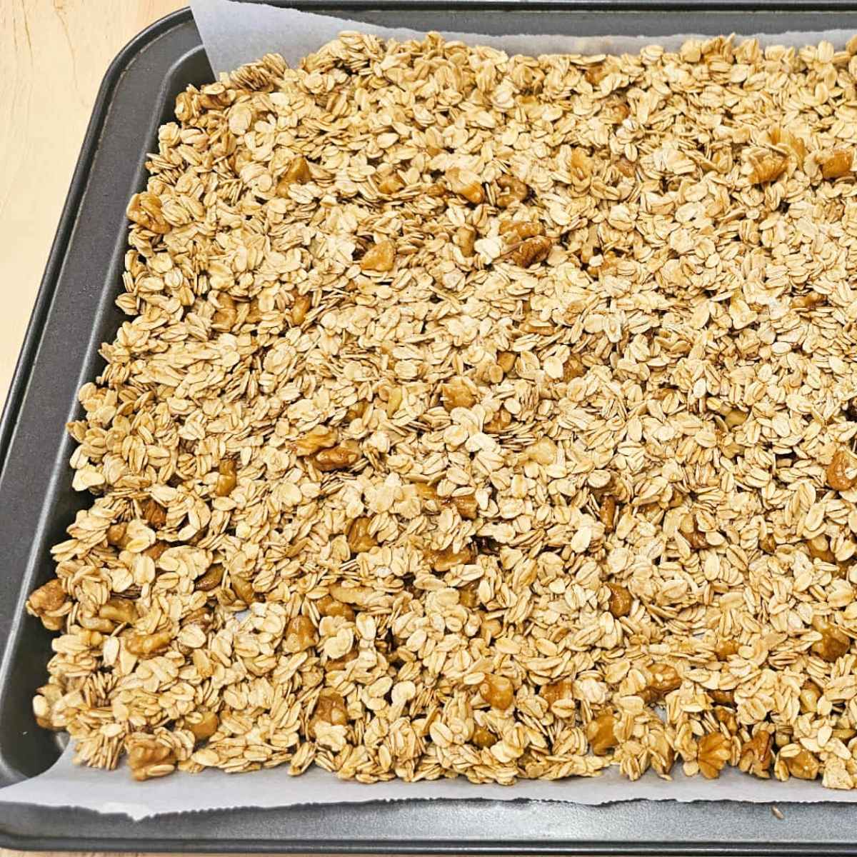 maple walnut granola spread out evenly on the baking sheet