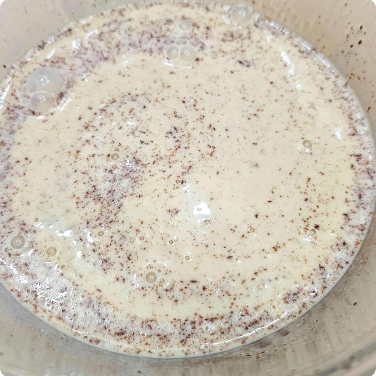 Batter ingredients mixture for the French toast, mixed and sitting in a clear glass bowl on a wooden counter top