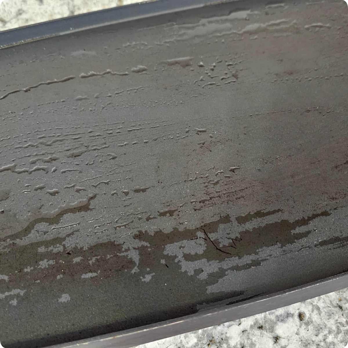 Electric griddle, heated and lightly coated with vegetable oil and sitting on a white and grey counter top