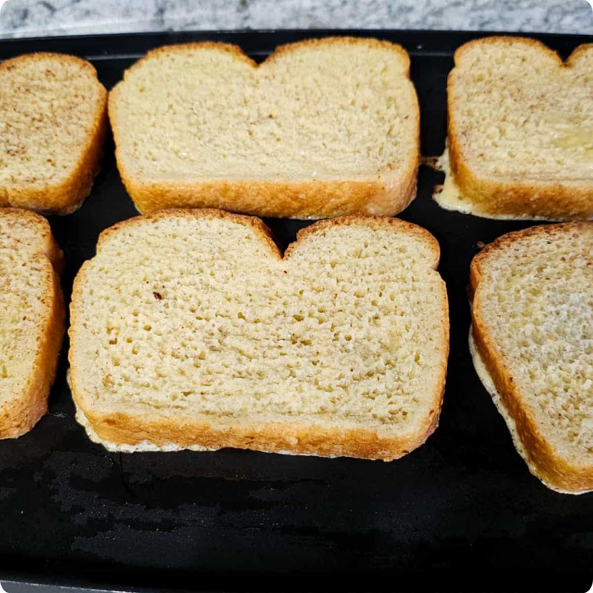 French toast cooking on the electric griddle that's sitting on a white and grey counter top