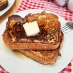 easy French toast recipe sitting on a white glass plate on a red and white checkered cloth napkin