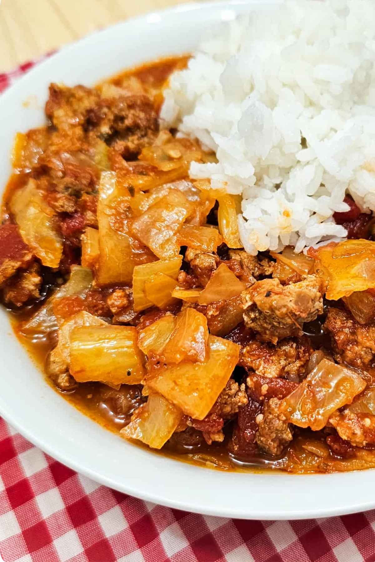 unstuffed cabbage rolls with a scoop of Jasmin rice on top in a white bowl with a red and white checkered cloth napkin under it