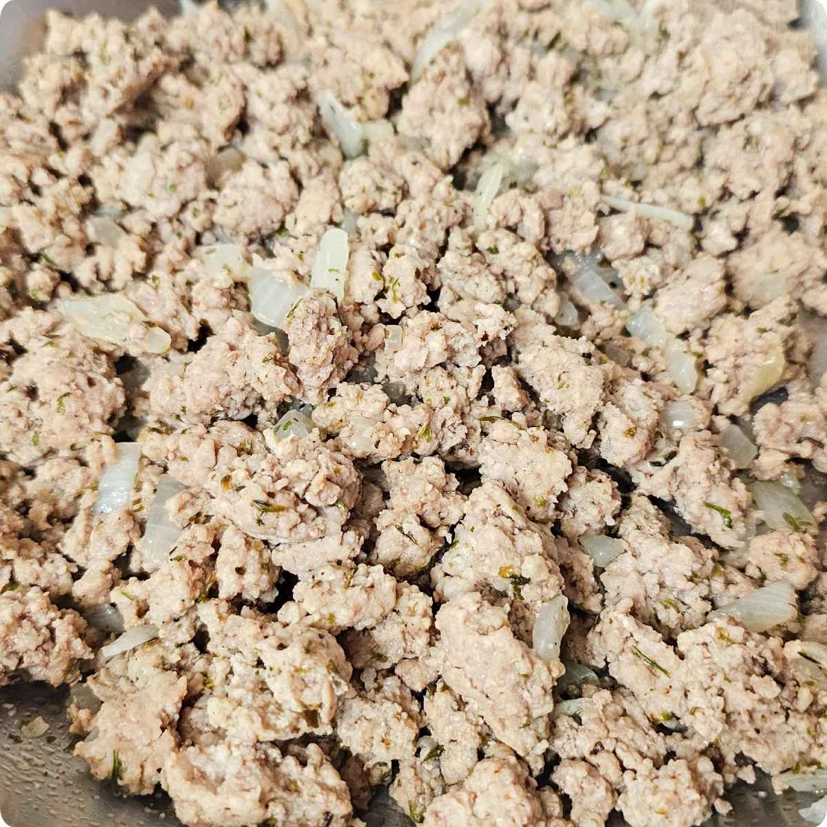 cooked ground pork and onions in a large stainless steel pan