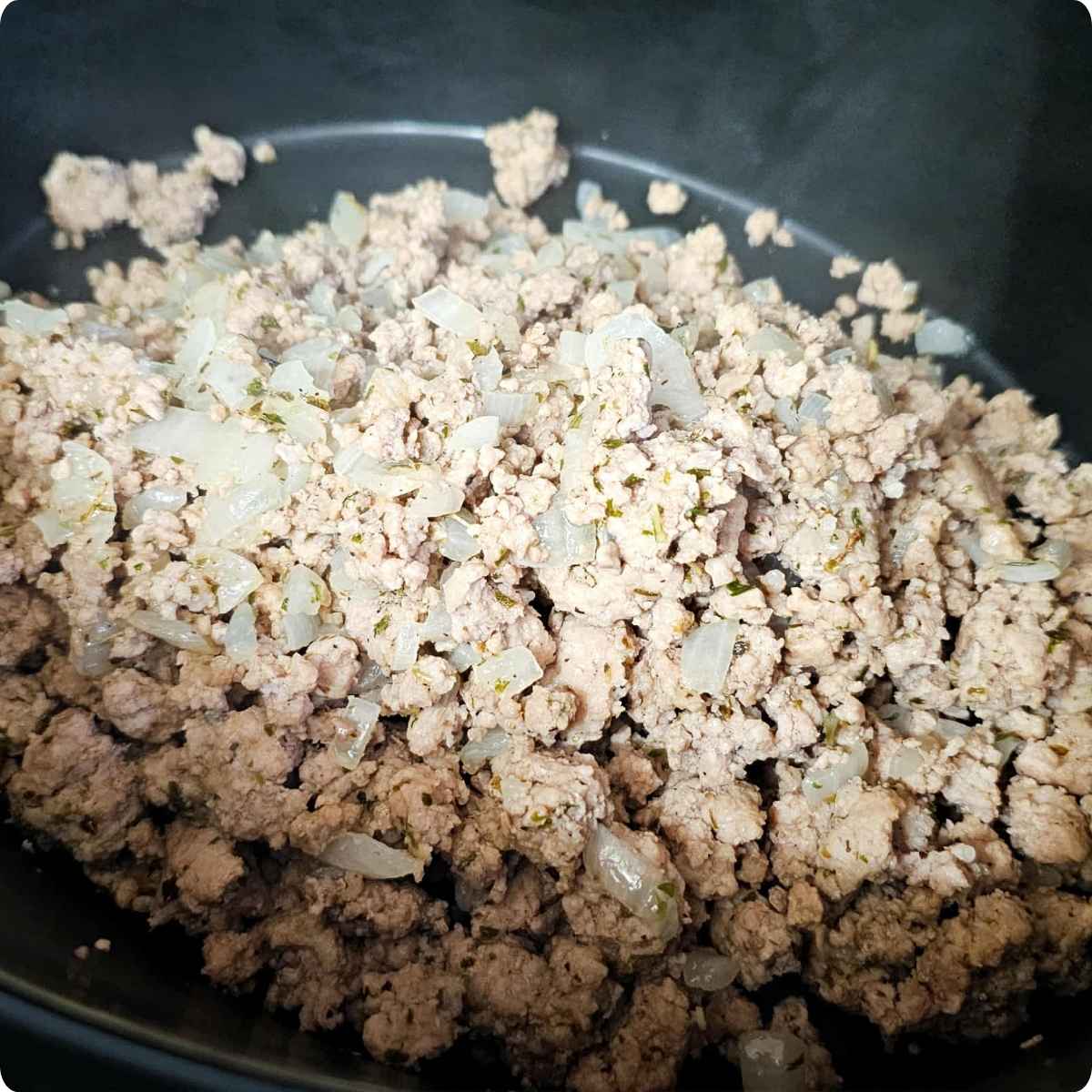 ground pork and onions in the bottom of the crock pot