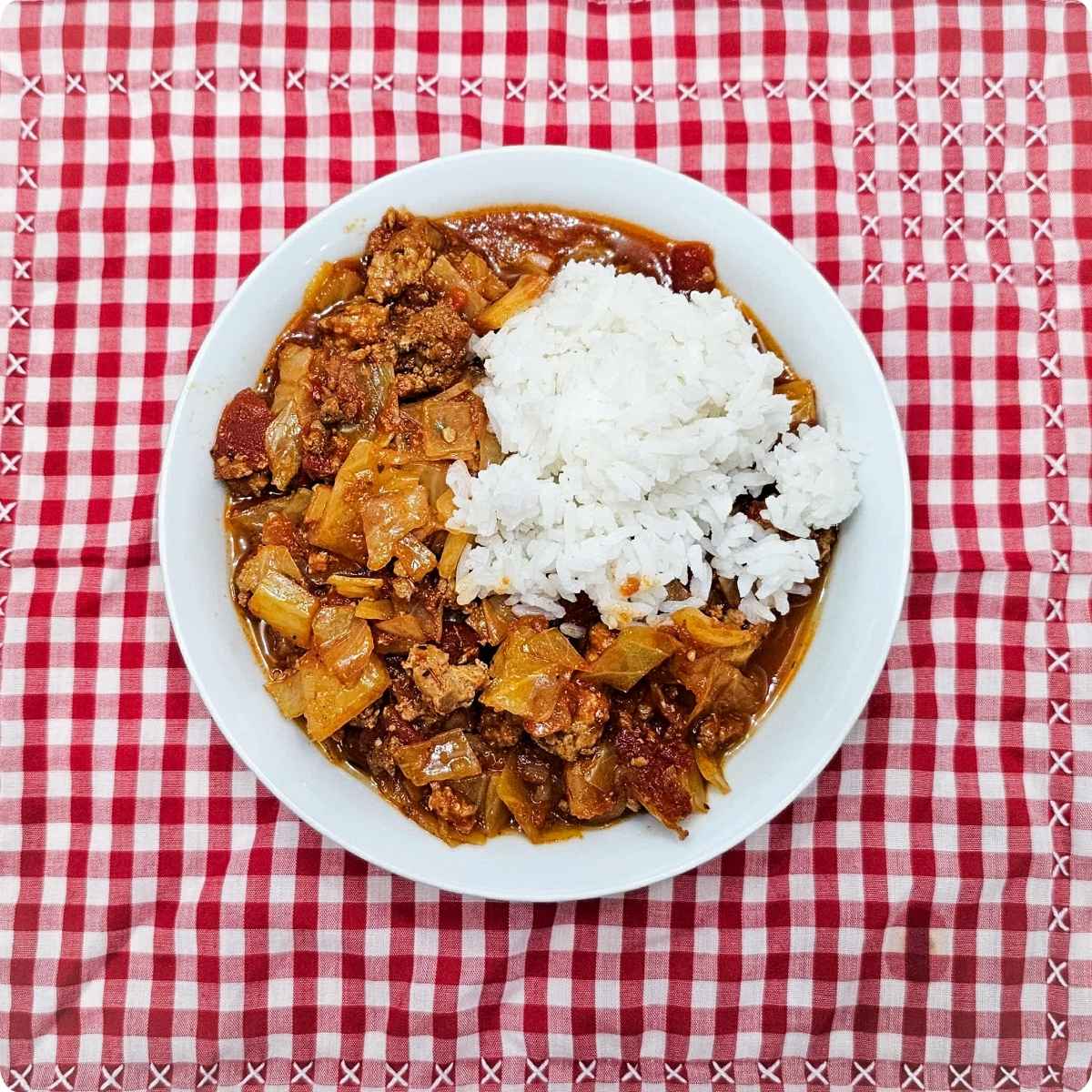 unstuffed cabbage rolls sitting on a red and white checkered table cloth with a scoop of Jasmin rice on top