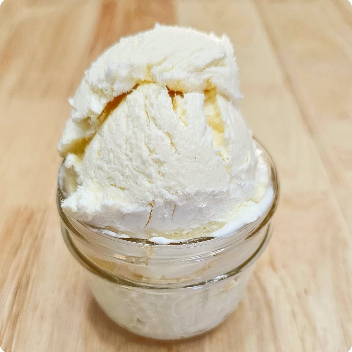 no churn vanilla ice cream in a small mason jar sitting on a wooden counter top